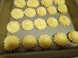 14、原味曲奇饼干,挤入烤盘中,并间隔缝隙,(手法:手握裱花袋,垂直的往下挤,挤到自己想要的大小时停止,将裱花袋转个圈,裱花袋里面饼干糊自然和挤出来的饼干断开)