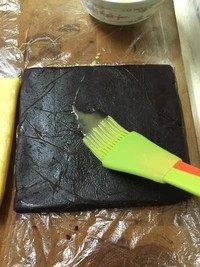 9、马赛克饼干,取出两个冻好的面团，用剪刀分别剪开两个保鲜袋的一面。在其中一个面团上，涂刷一层蛋液（分量外）。保鲜袋不要扔掉，整形的时候借助它不粘手，不散形，很有用。