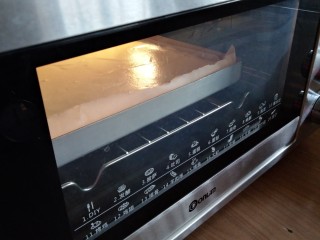 9、圣诞树根蛋糕,倒入铺了油纸的正方形烤盘里，在桌面上震几下，震出气泡，放入已经预热好上火170度下火175度的东菱烤箱，中下层烘烤18分钟左右