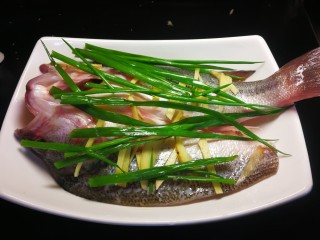 13、千张鲈鱼,葱前段和剩下的姜片切丝放在鱼的上当。锅内放水烧开，水开后把鱼放入大火7分钟关火闷一分钟