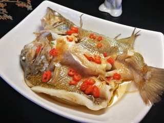 15、千张鲈鱼,小米椒切小圈，摆放在鱼身上，然后锅内油烧冒烟，趁佩服均匀倒在鱼身上，激发出香味。