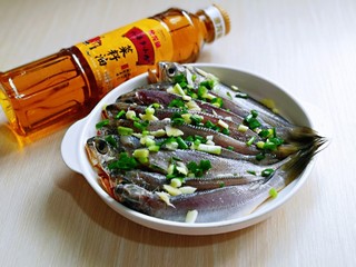 2、酥炸小黄鱼,葱姜切碎，均匀撒在鱼身上。