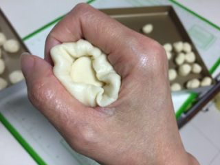 13、豆沙蛋黄酥,用右手的虎口包好。