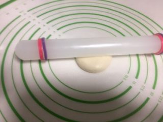 16、豆沙蛋黄酥,收口的地方朝上,用手压一下,擀面杖放在面团中间。