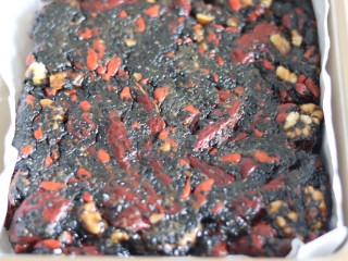 13、自制阿胶糕,烤盘里垫油纸，把做好的阿胶糕装进烤盘里，稍微冷却后，按压平整。