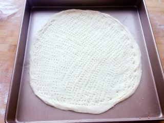 9、培根卷大虾披萨,把面饼放到烤盘上，用叉子在饼皮上扎出小孔