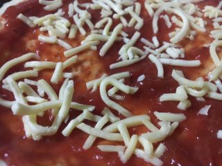 15、意式鲜虾烟熏香肠披萨,取出，在烤好的饼坯上刷上披萨酱，没有的话，蕃茄酱也可以。均匀的撒上马苏里拉芝士。再放入烤箱，烤5分钟至芝士融化。