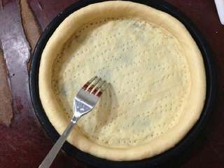 5、培根洋葱披萨,用叉子在面皮上叉些小孔,排气。