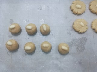 6、花生小酥饼,在每个小圆球上摆上半片花生仁,然后用手稍微轻轻按压成小圆饼;
