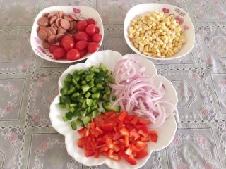 2、披萨,在饧发面时，来准备食材，玉米剥粒，小番茄切对半，香肠切薄片，青红椒切丁，香葱切细条备用。