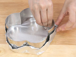 4、蓝莓益力多慕斯,这个慕斯我用慕斯圈来制作，所以需要包底，大家可以用锡纸，油纸，或者是保鲜膜把慕斯圈的底部包住，如果是直接用活底蛋糕模制作的朋友，直接把饼干碎倒进去就可以了