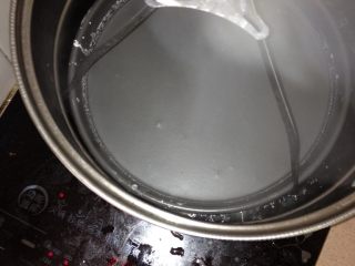 3、自制纯手工凉皮,取一锅水烧开 另取一披萨盘 取一勺澄面糊倒进披萨盘 转动盘使其铺均已 薄薄一层就好 放盘在开水里 看到面糊变色起泡就熟了 