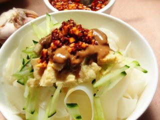 6、自制纯手工凉皮,将皮切成自己想要的宽度 黄瓜擦丝 蒸好的面筋切块 大蒜拍碎加凉开水泡一会儿加适量盐及芝麻油作为大蒜水 浇在凉皮上 加两勺芝麻酱 一勺辣椒油 一勺醋  嗯 很棒 跟小时候的味道一样