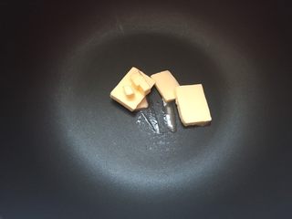1、冰爽绿豆糕,黄油切片入不粘锅内，加热至融化。