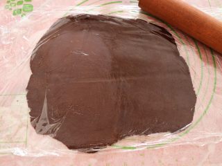 10、熊猫饼干,将可可色面团铺在硅胶垫上，上下各覆盖一层保鲜膜，用擀面杖擀成厚度大概3mm厚的面皮；