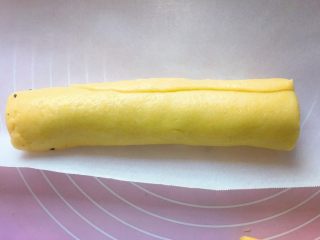 10、黑芝麻饼干,从顶部开始卷起,卷紧成长条,用油纸包上,放入冰箱冷冻一小时。