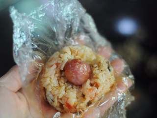 4、圣诞老人便当,炒好的米饭放在保鲜膜上,将一小节香肠摆在中间