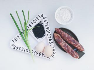 1、腊肠煎饼果子,食材准备:鸡蛋2个 腊肠2根 黑芝麻适量 小葱1棵 面粉100克 菜籽油适量 食盐适量