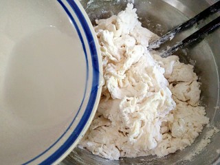 2、做饼+手撕披萨――万能的平底锅就能造,将干酵母用温水冲开，少量多次加入面粉中，用筷子搅拌成雪花状。