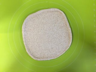 9、黄桃全麦披萨,取出发酵好的面团，在揉面垫上擀扁排出气体，盖上保鲜膜醒发10分钟