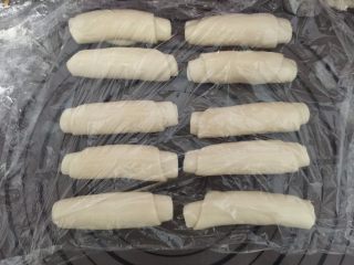 10、莲蓉蛋黄酥,慢慢卷起来，10个都一样操作，全程用保鲜膜盖好松弛20分钟