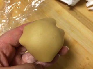 12、#甜味#莲蓉蛋黄月饼,月饼皮用手掌心按扁，中间薄两边厚，放入包好的莲蓉蛋黄，反扣过来，如图