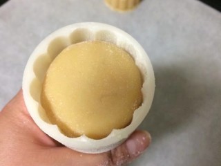 15、#甜味#莲蓉蛋黄月饼,50g的磨模具放入压花，撒入少许粘米粉，再把多余的粉磕掉，放入做好的月饼，注意放入时不要让模具的棱角刮到面团