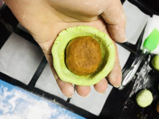 1、#咸蛋黄肉松青团#,拿一个剂子，如图包馒头的方法，边口一定要薄，重合的口子朝下放