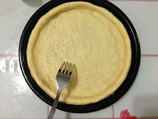 7、培根松茸披萨,把面皮做成型。 再用叉子叉些孔。