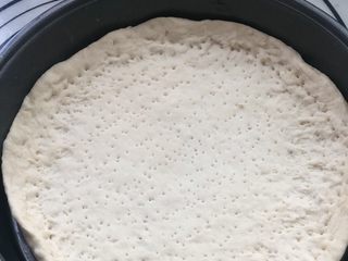 6、意式烤肠披萨,擀成圆形饼坯，放入披萨烤盘，四周略高，用叉子叉出均匀的孔，避免受热膨胀鼓起。