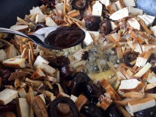 14、海鲜卤面,把煸炒好的食材扒在锅的一边，锅的中间留出来，放入1勺的天津甜面酱，小火把甜面酱炒出香味。