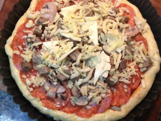 10、肉香满溢披萨,开始放馅料:最底层刷蕃茄酱(披萨酱)--马苏里拉奶酪丝--口蘑片--香肠片--培根片--马苏里拉奶酪丝。最后将披萨四周边缘,约1cm空白面饼边上刷一层蛋液。