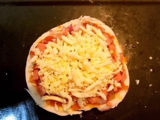 12、剩馒头的春天  馒头火腿披萨,最后再撒上一层芝士碎即可，逐一做好另外2片馒头，把做好的披萨坯放入烤盘