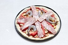 5、薄底鲜虾培根披萨,将红椒丝摆上，再摆上一半鲜虾仁，培根，在表面磨入黑胡椒和海盐适量