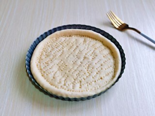 13、培根火腿披萨,取一块面团，用擀面杖擀圆饼，与自己的披萨盘一样大小即可哈，再用食品叉扎出不规则的洞洞眼。