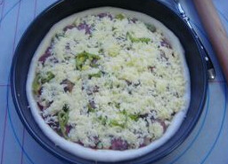 6、简易腊肠披萨 ,将腊肠和青豆玉米青椒摆满后，撒上剩余的芝士丝，再撒些芝士粉，烤箱提前预热200度，入炉烤25分钟