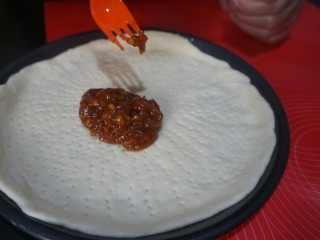 11、独家秘制香肠披萨,将提前熬好的披萨酱，取一勺放在披萨饼底部。