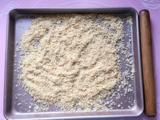 2、花生酥～#家有烤箱#,将熟花生米放在烤盘中，用擀面杖压碎，不要压成泥，稍微带点颗粒，吃起来口感更好。