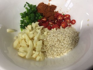 7、手撕鸡胸肉,空碗里放入大蒜头,小米椒,葱花,白芝麻,辣椒粉一勺