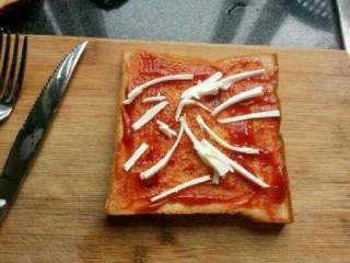 8、自创【煎酿土司披萨】,拿一块面包把番茄酱抹均匀，在放上奶酪。