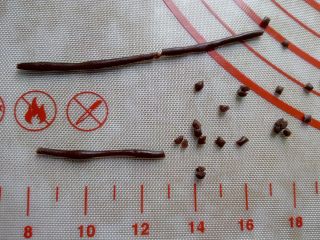 15、古筝情韵,取出后用可可面团搓一条细的长条,切小段,揉成很小的21个小圆球。依次按照从筝头到筝尾依弧线放到古筝上,做筝柱,再烤2分钟。