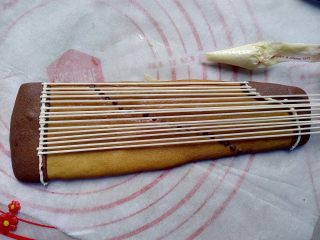 16、古筝情韵,晾凉后,用融化的白巧克力,涂在古筝的两端合适位置上,放上龙须面,固定在古筝上做琴弦。