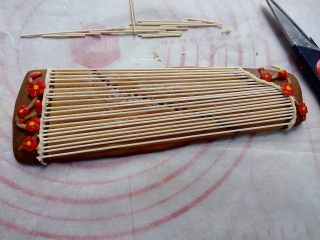 17、古筝情韵,用咖啡色翻糖做树枝,蘸点巧克力粘在在古筝的两头,用红色翻糖做些小花,把花朵随意摆放到树枝上。