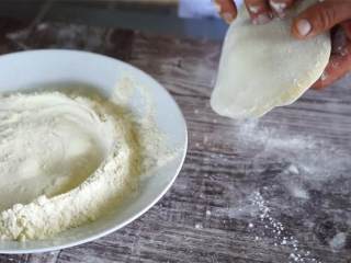 1、卡布里乔莎披萨,在工作台上撒上适量面粉，用手抹开。放上披萨面团 (240 克) ，用手指轻柔地展开。