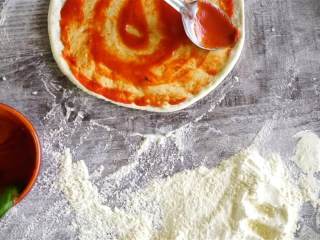 9、卡布里乔莎披萨,用同一只勺子，舀大约5大勺的番茄酱到面团中央，用勺子背面从中心向外沿抹开。