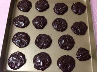 6、年味――趣多多可可曲奇,用勺子挖取15克左右的面糊排入烤盘，用勺子背把面糊轻轻压平、整形，表面用巧克力豆做装饰，烤箱180度预热