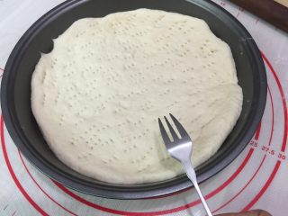 10、牛肉田园披萨,11. 将面团按圆按扁成饼状,尽量让饼皮的厚度均匀,把饼皮用叉子在饼皮上扎满小孔