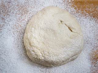 1、玛格丽特披萨,将事先做好的披萨面团放在撒有面粉的案板上。