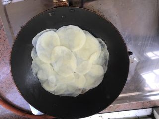 3、特制土豆披萨,先将土豆铺满整个平底锅，慢火煎，煎1-2分钟就先涂一层番茄酱，然后将材料一层一层的往上放，最后放芝士