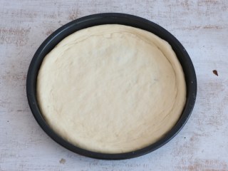 5、培根披萨,披萨盘抹油，将发酵好的面团，用擀面杖擀成与盘底一样大小的饼底，把饼皮铺进去。